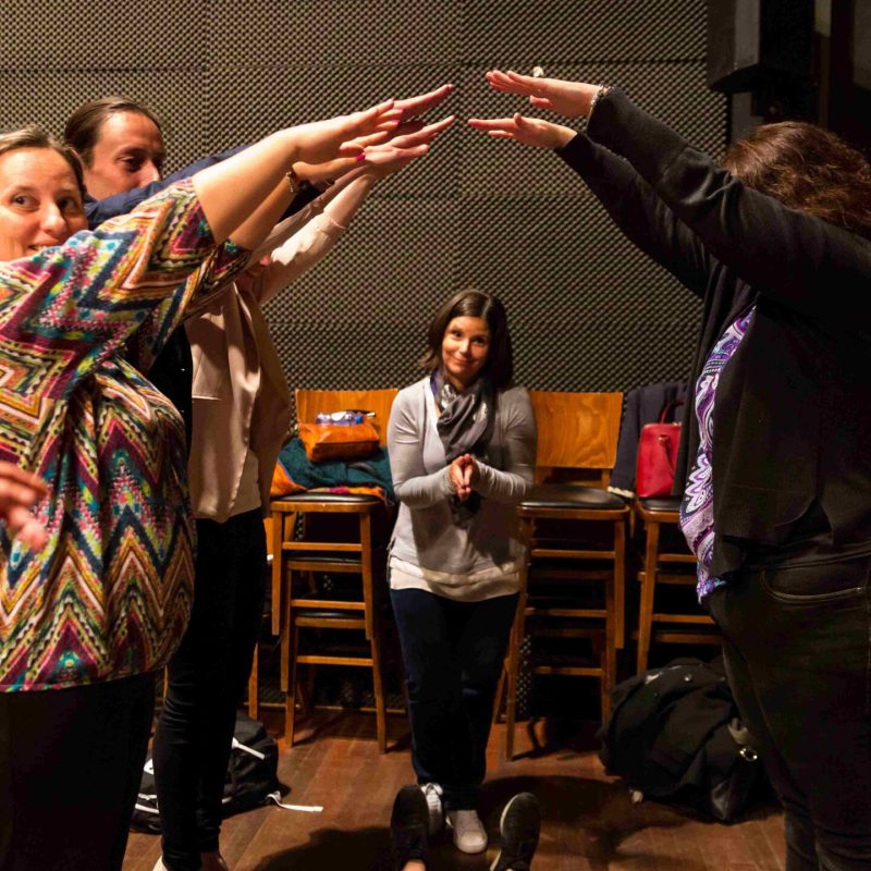 A group of people standing in a room completing a team building activity