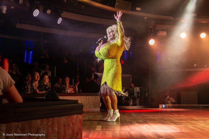Performer in yellow dress sings on stage with audience watching.