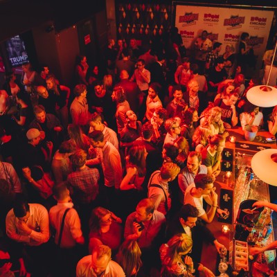 A crowded bar with people socializing under warm lighting.