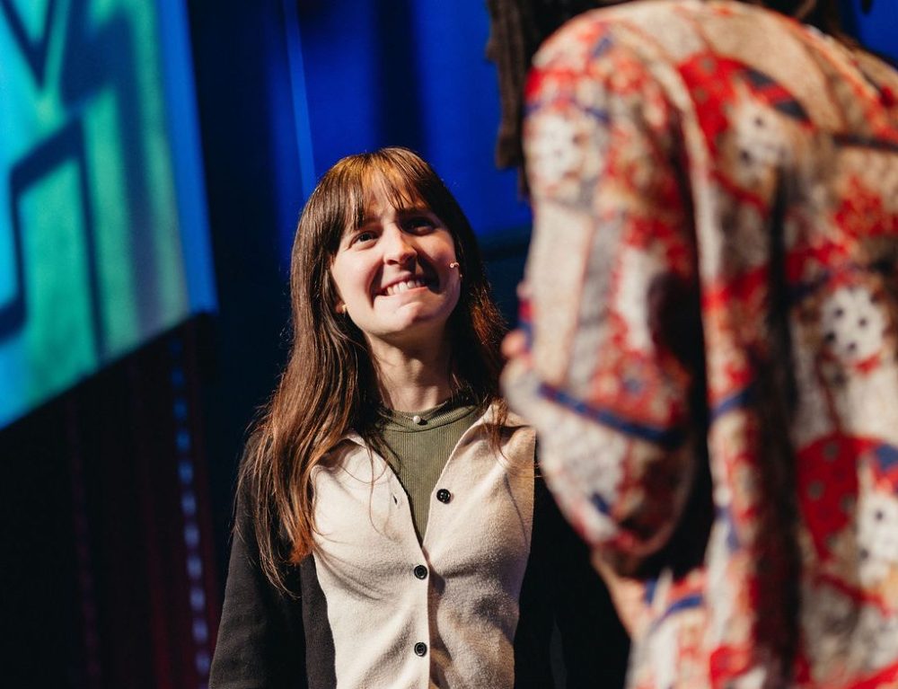Two people on stage, one smiling and the other in a colorful shirt.