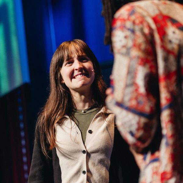 Two people on stage, one smiling and the other in a colorful shirt.