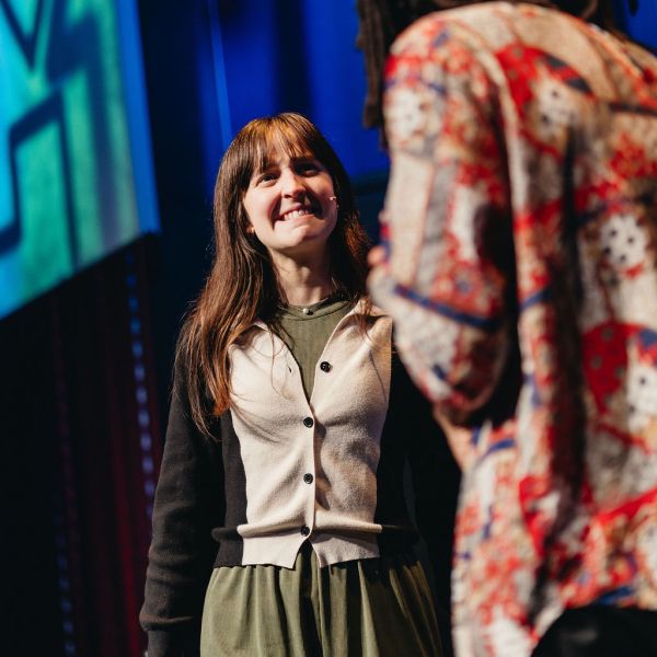 Two people on stage, one smiling and the other in a colorful shirt.