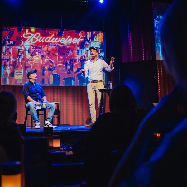 a group of people sitting on a stage in front of a laptop computer