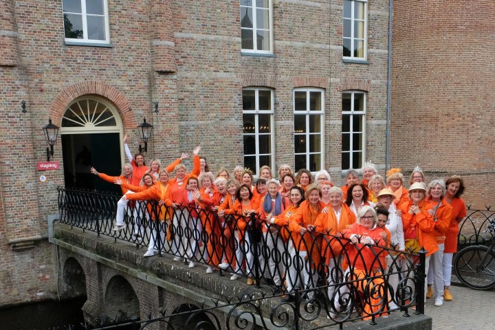Group of people in orange clothing posing on a bridge.