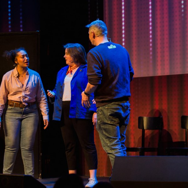 a person standing on a stage in front of a curtain