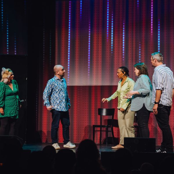 a group of people standing on a stage in front of a curtain