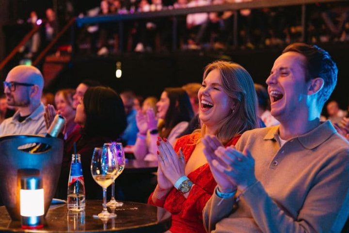 Audience clapping and laughing at a comedy show.