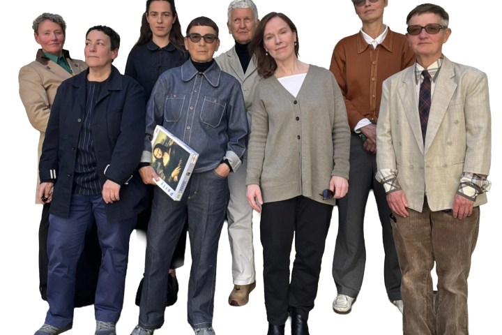 Group of eight people posing, wearing casual and formal clothing on a white background.