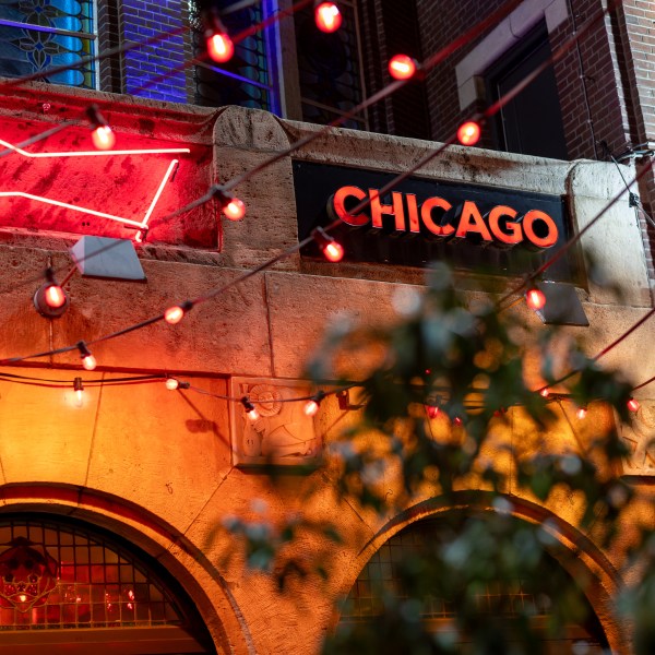 Neon-lit Chicago sign and string lights on a brick building facade at night.
