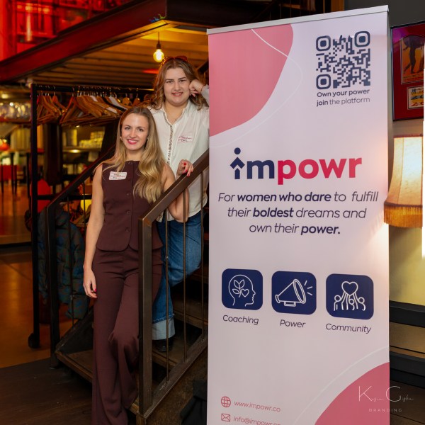 Two people stand beside a banner for impowr, a women's empowerment platform.