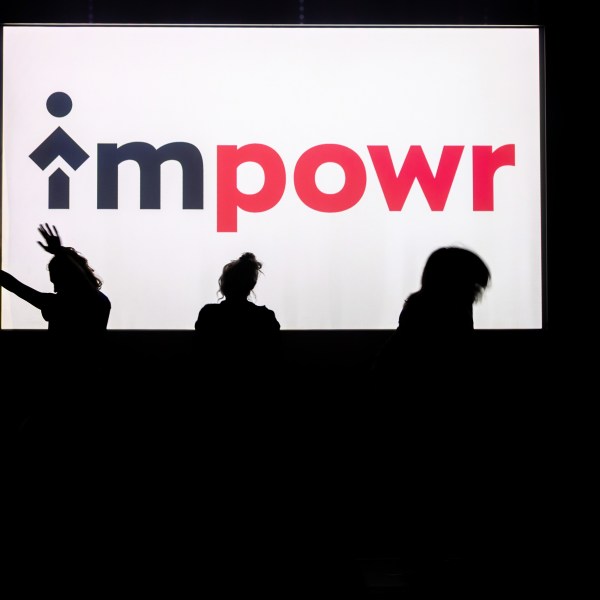 Silhouettes of three people dancing in front of a screen displaying the word 'impowr'.