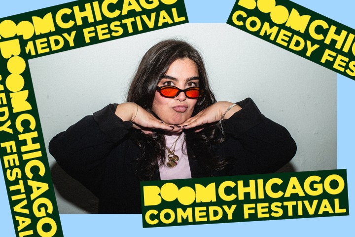 Person poses playfully with hands under chin, wearing red sunglasses, surrounded by Boom Chicago Comedy Festival banners.