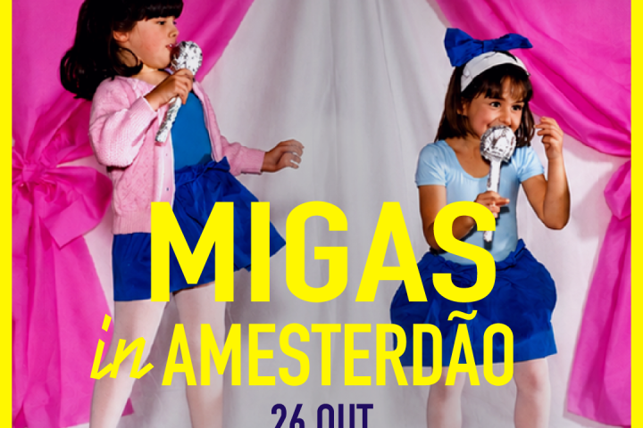 Two young girls in blue costumes perform on stage with pink curtains.